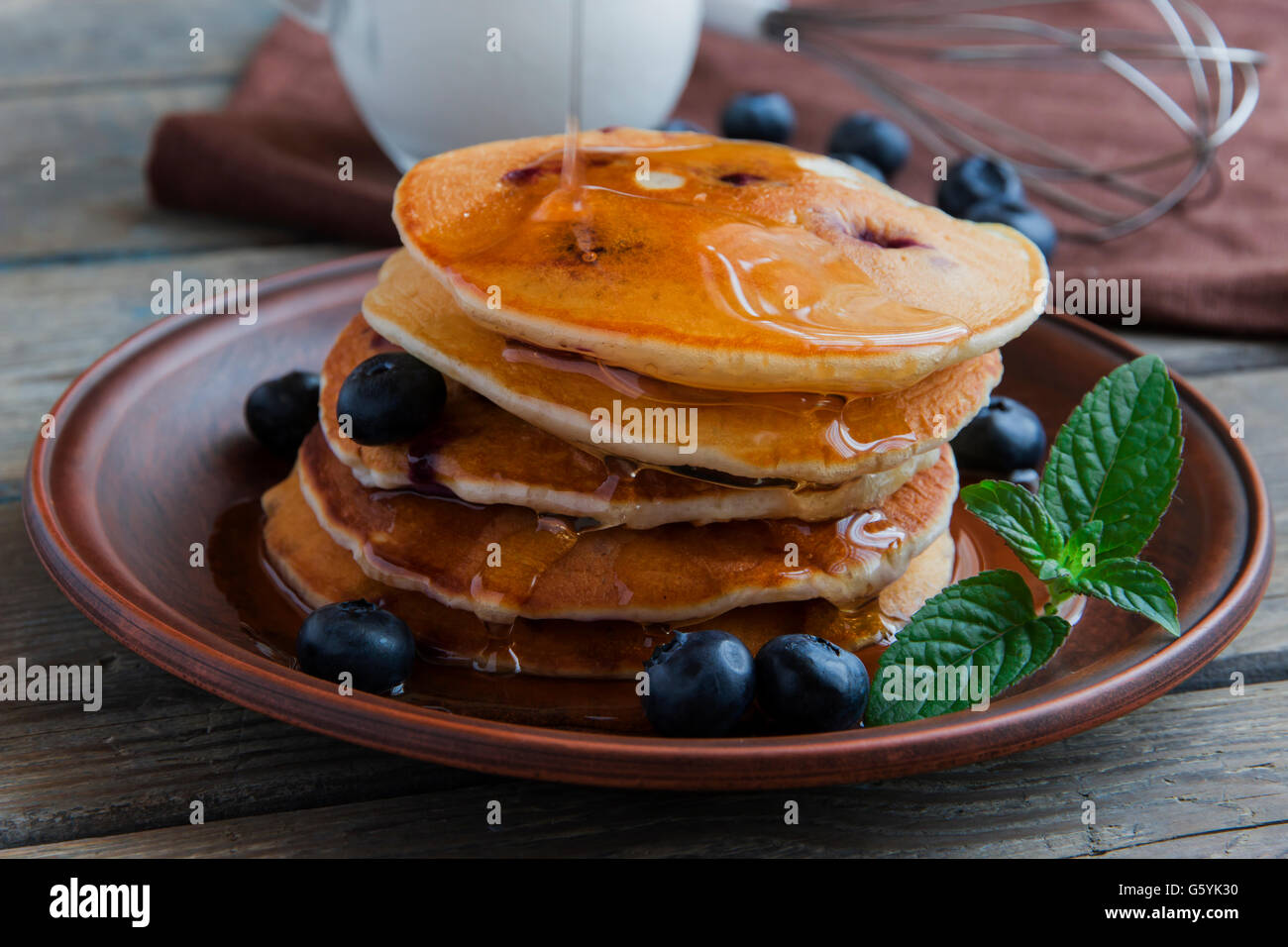 Frittelle di mirtillo su una piastra Versare lo sciroppo d'acero Foto Stock