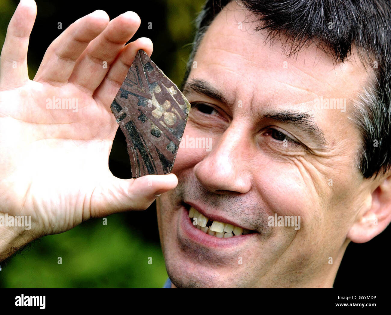 Dr Paul Stamper, English Heritage Ancient Monuments Inspector, contiene un pezzo di raro vetro medievale del 14 ° secolo scoperto da conigli burrowing, che si pensa siano venuti da una casa padronale in Warwickshire. Foto Stock