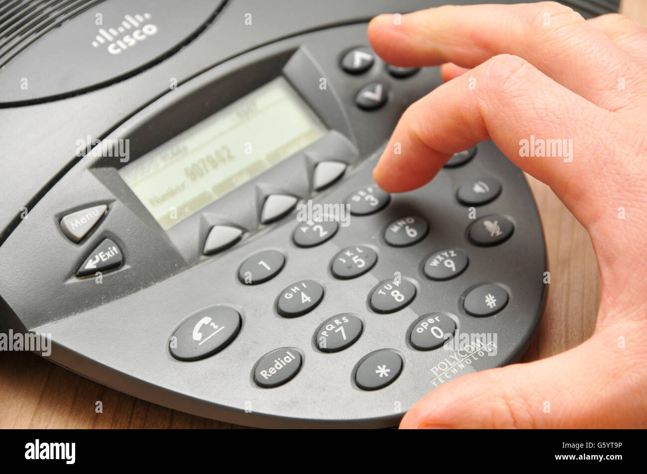 Un dipendente di sesso maschile compone un numero di telefono in una conferenza chiama il telefono durante una riunione Foto Stock