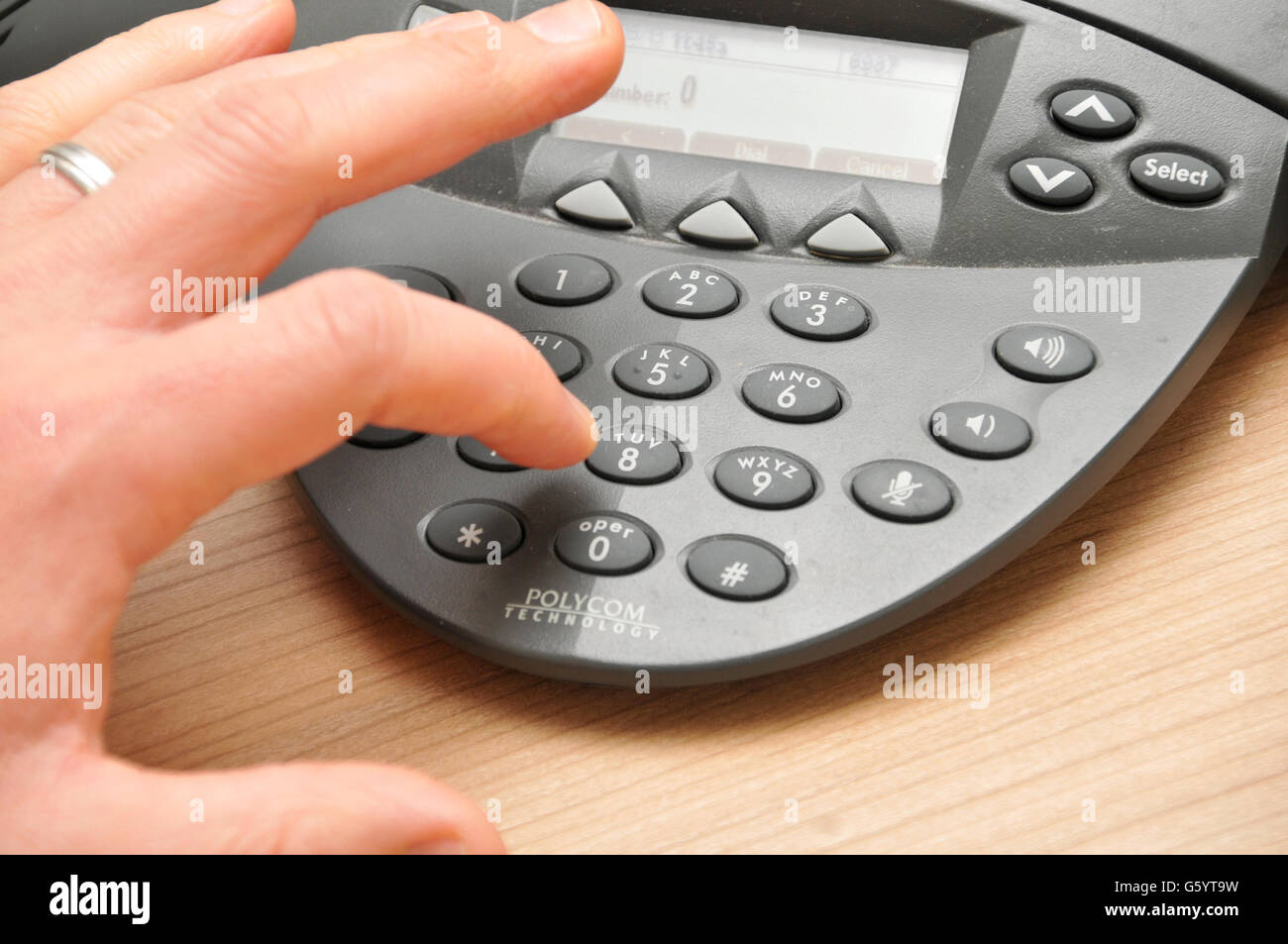 Un dipendente di sesso maschile compone un numero di telefono in una conferenza chiama il telefono durante una riunione Foto Stock
