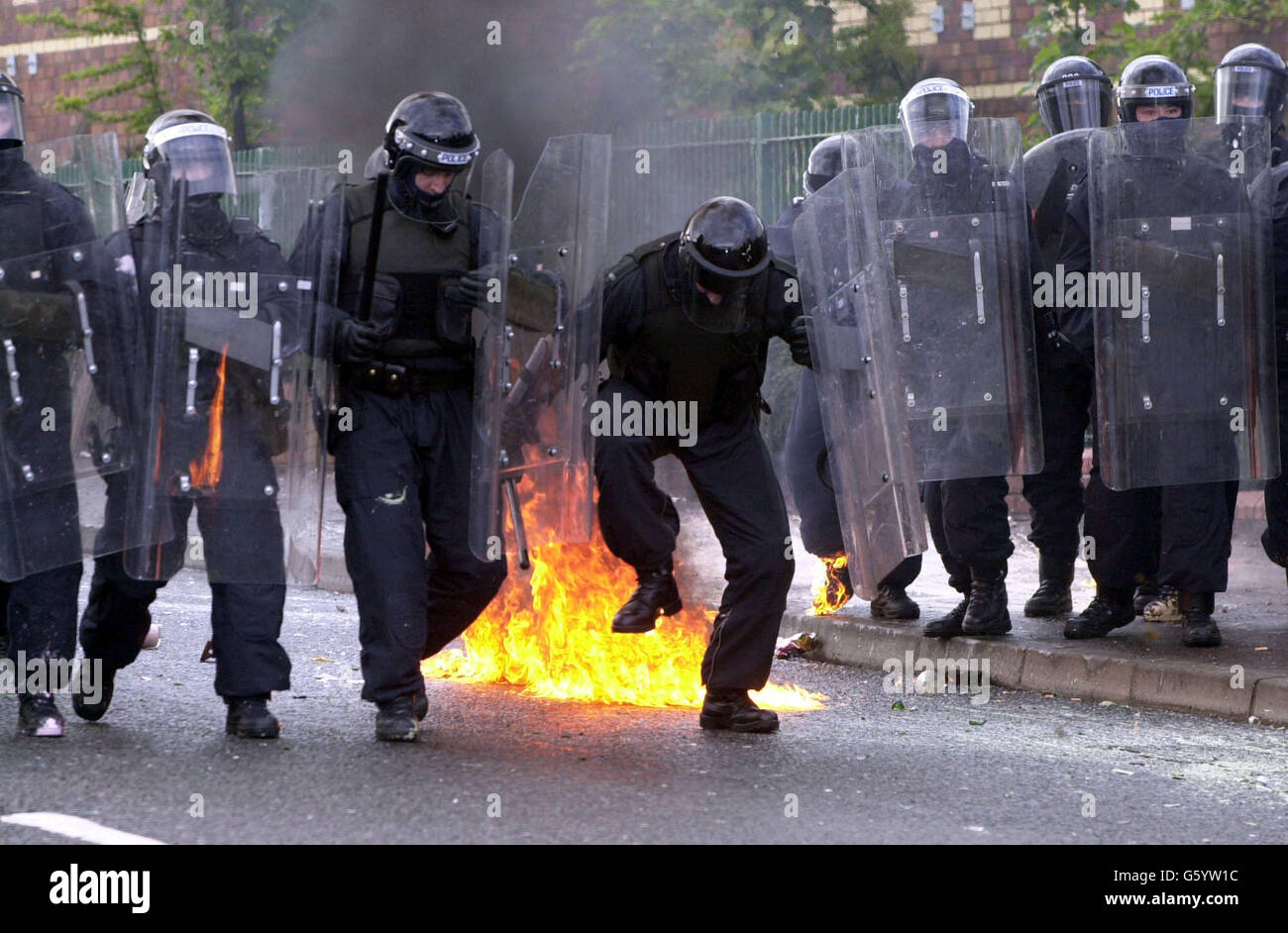 Un poliziotto estizza le fiamme dopo essere stato colpito da una bomba a benzina sulla Springfield Road, a ovest di Belfast. La polizia ha sofferto una sbarramento di bombe a benzina, fuochi d'artificio e mattoni dopo che gli ufficiali hanno sparato un bastone di plastica ai dimostranti che hanno attaccato una parata di ordine arancione in un'area nazionalista. I problemi sono iniziati quando i manifestanti cattolici hanno visto Orangemen salire su una parte contesa della Springfield Road. Foto Stock