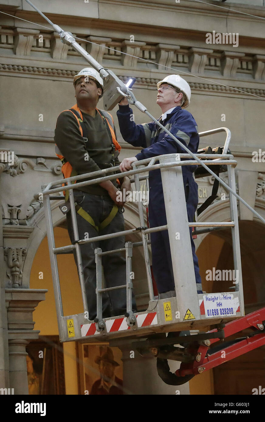 L'ingegnere Bill Kermack (a sinistra) e l'operatore John Laird (a destra) controllano i cavi di sospensione che tengono uno Spitfire alla Kelvingrove Art Gallery and Museum di Glasgow, Scozia. Foto Stock