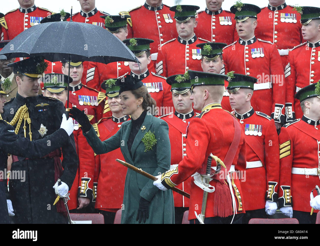 Il Duca e la Duchessa di Cambridge visitano la prima Guardia Irlandese del Battaglione per assistere alla Parata di San Patrizio a Mons Barracks, Aldershot, mentre la Duchessa viene consegnata un ombrello dopo aver posato per una fotografia ufficiale. Foto Stock