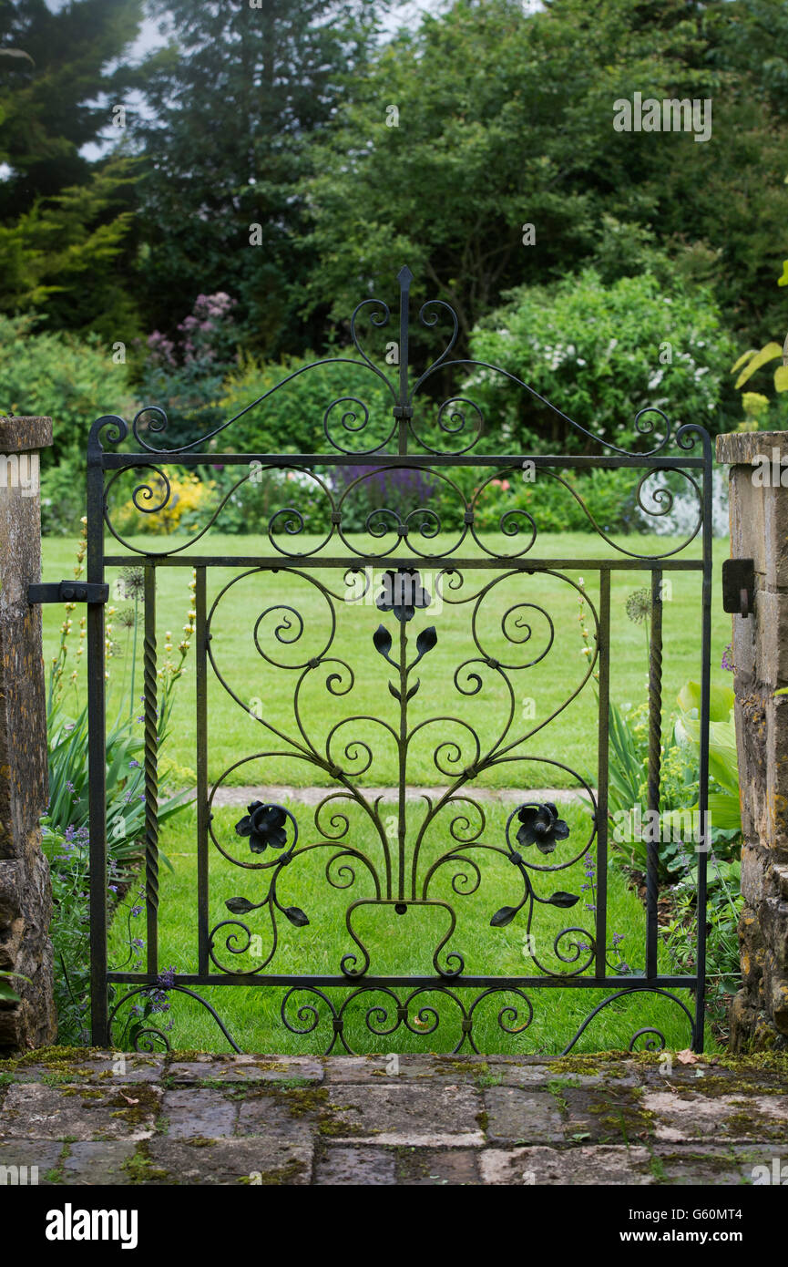 Decorativi in ferro battuto cancello in un giardino di Cotswold. Cotswolds, Inghilterra Foto Stock