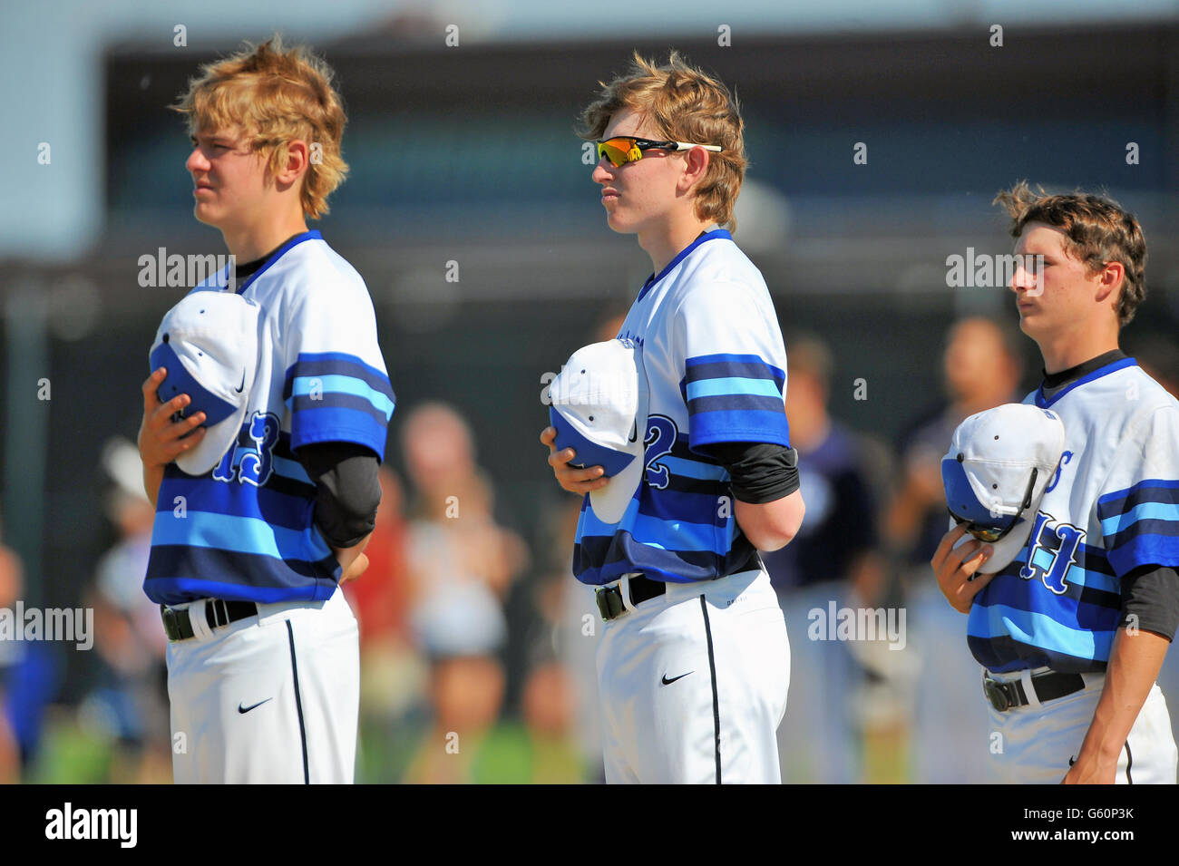 Prima di prendere il campo per una scuola di baseball gioco di spareggio giocatori per mettere in pausa la riproduzione di un inno nazionale. Stati Uniti d'America. Foto Stock