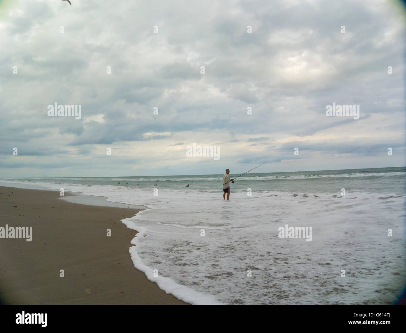 Pellicani e uomo vecchio costiera di pesca con raccolta nubi a Melbourne Beach, Florida, Stati Uniti d'America Foto Stock