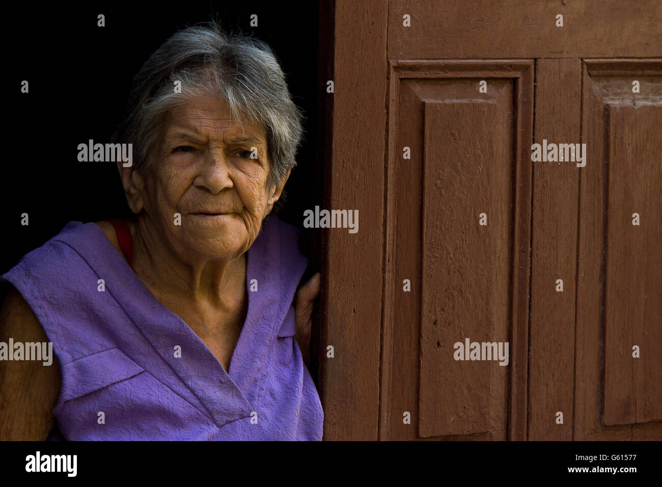 Un anziano donna vede attraverso la sua porta a l'Avana Centro Foto Stock