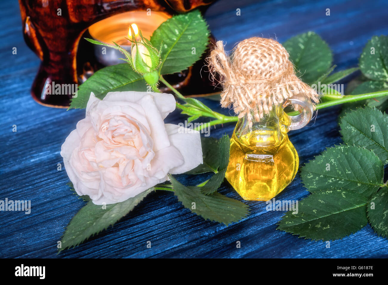 Olio essenziale di rosa sul blu scuro dello sfondo in legno Foto Stock