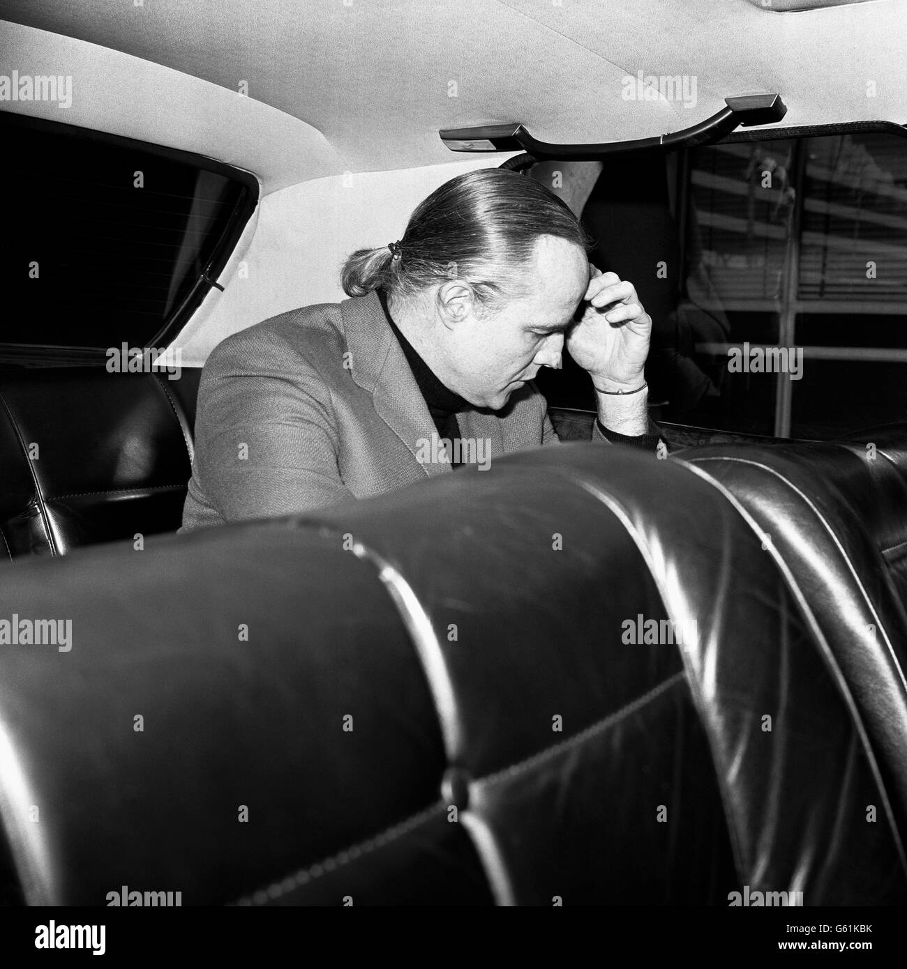 L'attore americano Marlon Brando, con i capelli tirati indietro in una coda di pony, fa un'immagine di profondo pensiero all'aeroporto di Heathrow, Londra. Partiva per New York. Foto Stock