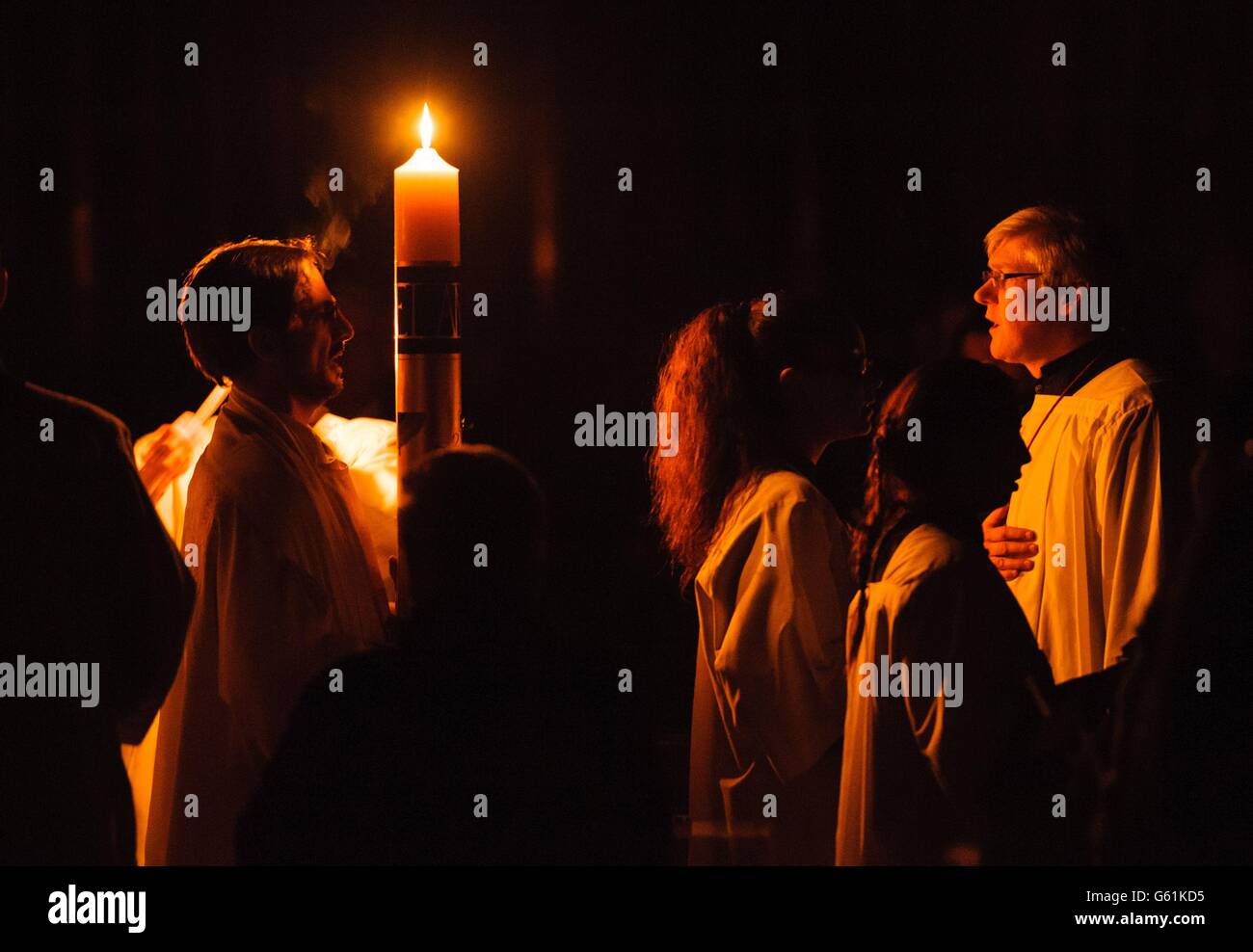 Il clero porta la candela pasquale durante la Messa della Veglia pasquale, presso la Cattedrale di Westminster, nel centro di Londra. Foto Stock