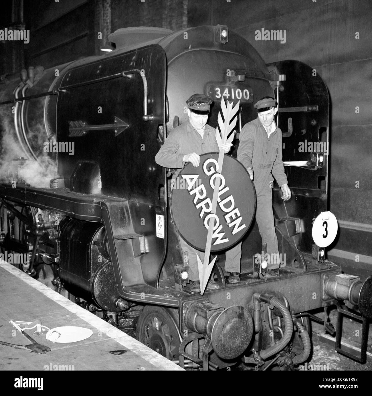 Dopo molti anni di servizio fedele, il trasporto a vapore ha fatto la sua ultima apparizione sul crack All-Pullman 'frecce d'oro' del treno della regione meridionale, quando ha avvistato a uno stand-still nella Victoria Station di Londra. *con una certa quantità di cerimonia due montatori hanno rimosso i badge 'freccia d'oro' che per così tanto tempo sono stati portati su locomotori che trasportano questa espressione di crack. Qui si vede la rimozione della targa del nome dalla porta del fumetto della locomotiva. Da domani la freccia d'Oro lascerà Londra per la sua volata verso la costa dietro una potente locomotiva elettrica. Foto Stock