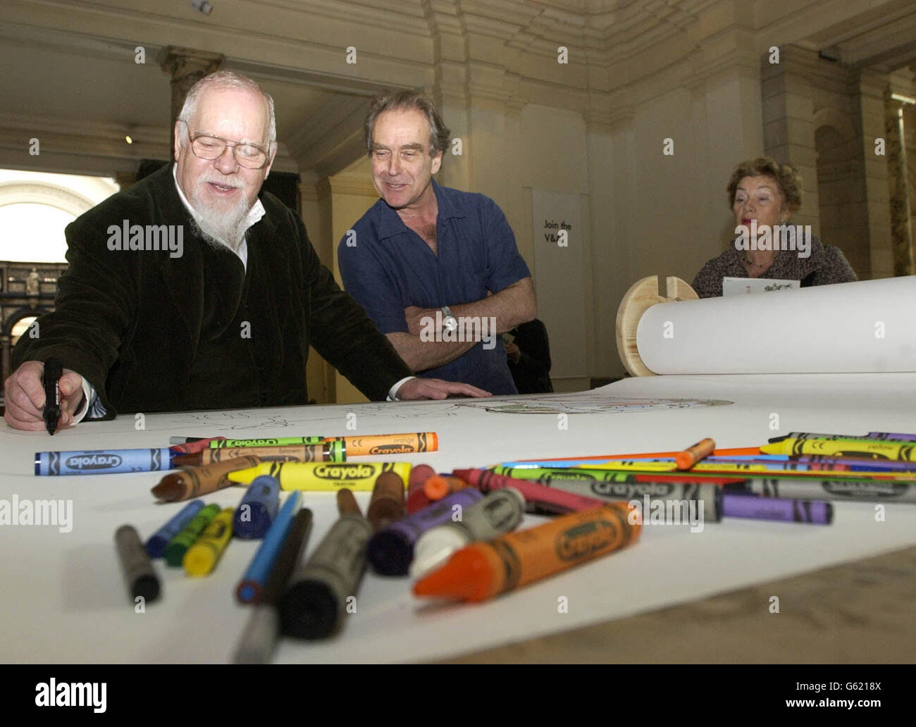 L'artista Peter Blake (a sinistra) abbonda sotto lo sguardo del fumettista Gerald Scarfe e un membro del pubblico al Victoria and Albert Museum di Londra per lanciare Draw the World, una campagna nazionale per ottenere il disegno paese. Foto Stock