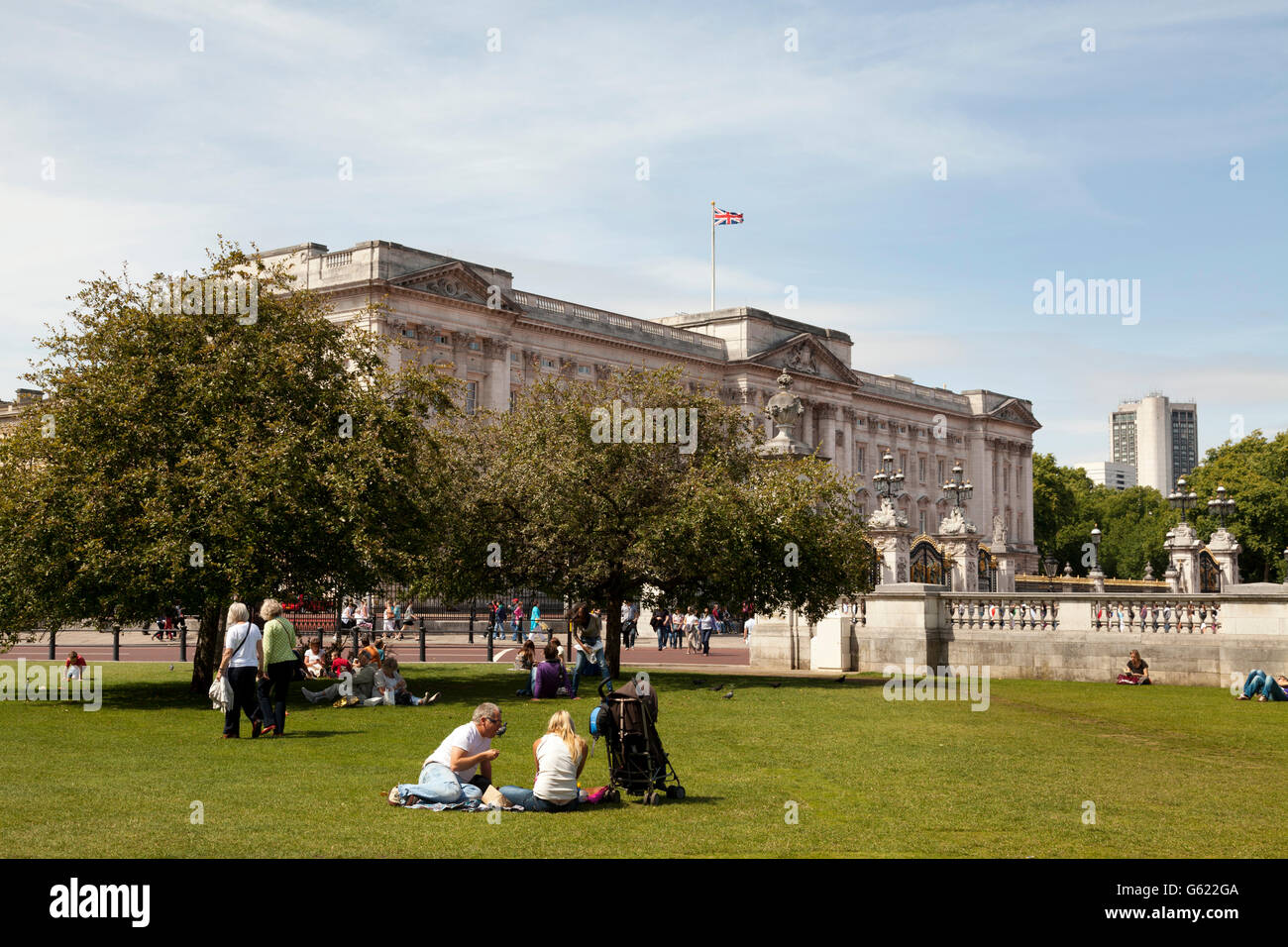 I turisti in appoggio sul prato fuori Buckingham Palace, London, England, Regno Unito, Europa Foto Stock