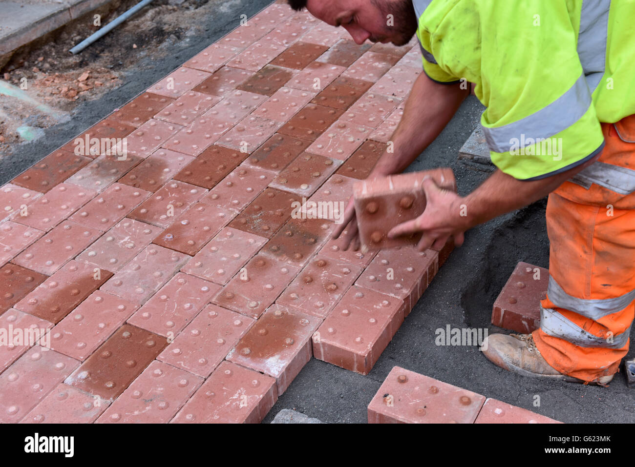 Workman posa di pavimentazioni tattili nel sentiero per assistere i non vedenti Foto Stock