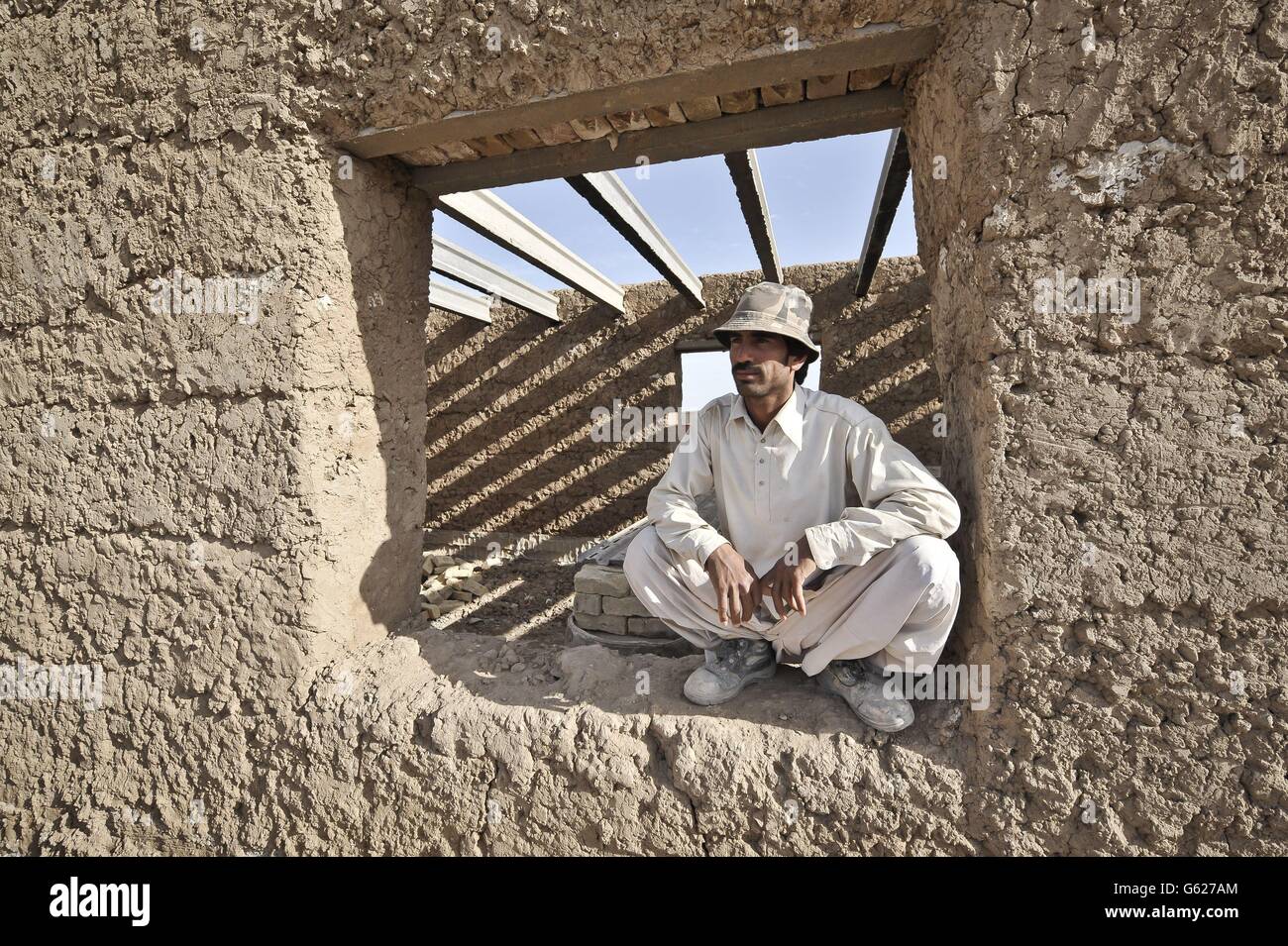 Un operaio edile nazionale afgano prende una pausa e guarda i suoi collaboratori da un'apertura finestra in un nuovo edificio a Patrol base Clifton, ora rinominato PB Oqab, Poiché ospita solo soldati dell'esercito nazionale afghano e viene costruito per soddisfare le loro specifiche esigenze, le forze ISAF iniziano a rimandare le basi e lasciano l'Afghanistan nel 2014. Foto Stock