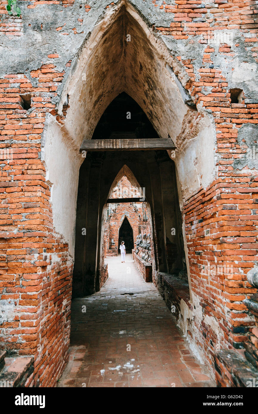 Una donna locale in bianco a piedi attraverso un tempio buddista in Ayutthaya sito Patrimonio Mondiale Foto Stock