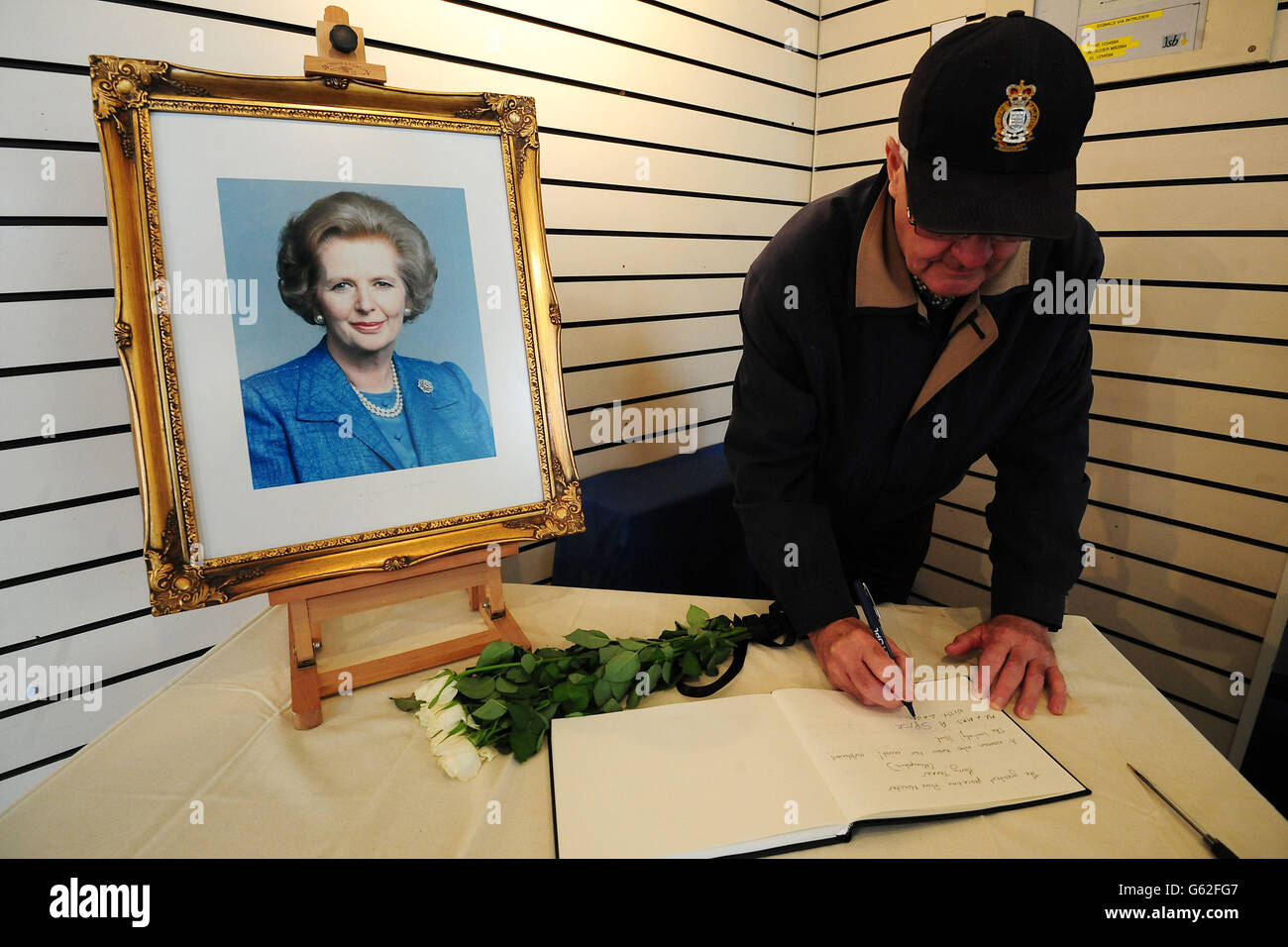 Un membro del pubblico firma un libro di condoglianze sotto un ritratto dell'ex primo ministro Baronessa Thatcher al Grantham Museum nella sua città natale Grantham. Foto Stock