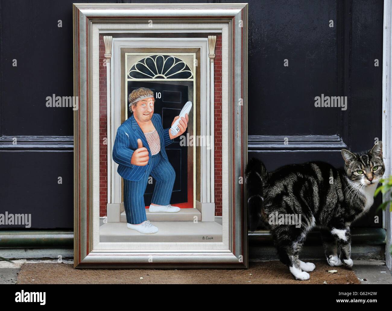 Un gatto graffia una stuoia mentre guarda un dipinto seduto a una porta dell'artista Beryl Cook che mostra il personaggio comico di Gregor Fisher Rab C Nesbitt che si trova fuori 10 Downing Street. Il lotto, che è stato valutato fra &libbra;6,000 e &libbra;8,000 fa parte della vendita contemporanea dei dipinti a Lione & Turnbull il 17 aprile. Foto Stock Un gatto graffia una stuoia mentre guarda un dipinto seduto a una porta dell'artista Beryl Cook che mostra il personaggio comico di Gregor Fisher Rab C Nesbitt che si trova fuori 10 Downing Street. Il lotto, che è stato valutato fra &libbra;6,000 e &libbra;8,000 fa parte della vendita contemporanea dei dipinti a Lione & Turnbull il 17 aprile. Foto Stock