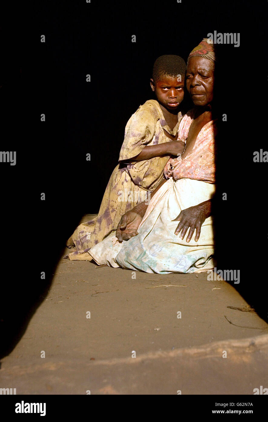 Mjiyasi Gungulou, 82 anni, conforta la sua bisnipote Mdakalira, 9 anni, alla quale fu lasciata cura dopo la morte per AIDS della nipote e del marito della nipote nel giro di un anno, nel villaggio di Nyande nel Malawi centrale. Le Nazioni Unite attualmente stimano 18.4 milioni di persone che soffrono la fame nella regione dell'Africa meridionale, e l'alta prevalenza dell'infezione da HIV rende le condizioni ancora più difficili. Foto Stock