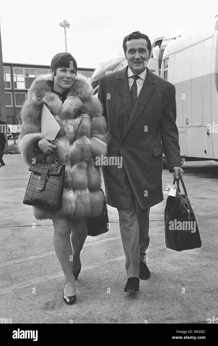 L'attore Patrick MacNee e sua moglie Catherine Woodville in un cappotto di pelliccia 'generoso' all'aeroporto di Heathrow. Foto Stock