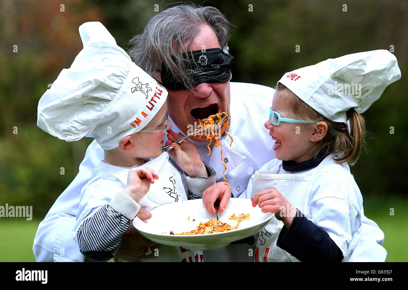 Lo chef della stella Michelin Derry Clarke riceve un cucchiaio di pasta dai piccoli chef Michael Kavanagh, Four, e Milla Williams, Four, in piazza Merrion, Dublino alla fotocellula per annunciare che ChildVision, il National Education Center for Blind Children, sarà il partner ufficiale di beneficenza per il Westport Festival of Music & Food 2013 sabato 29 e domenica 30 giugno. Foto Stock