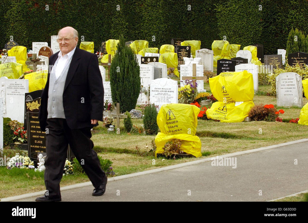 Un visitatore del cimitero di Sidcup cammina davanti alle pietre di testa ricoperte di sacchetti di plastica gialli perché gli ispettori che lavorano per il London Borough di Bexley li consideravano non sicuri. * circa 260 altre lapidi al cimitero sono state fissate perché erano in pericolo imminente di caduta, un portavoce del consiglio ha detto. L'azione fa parte di un controllo a livello nazionale dei memoriali da parte delle autorità locali, che è stato provocato da incidenti che coinvolgono la caduta di lapidi. Foto Stock