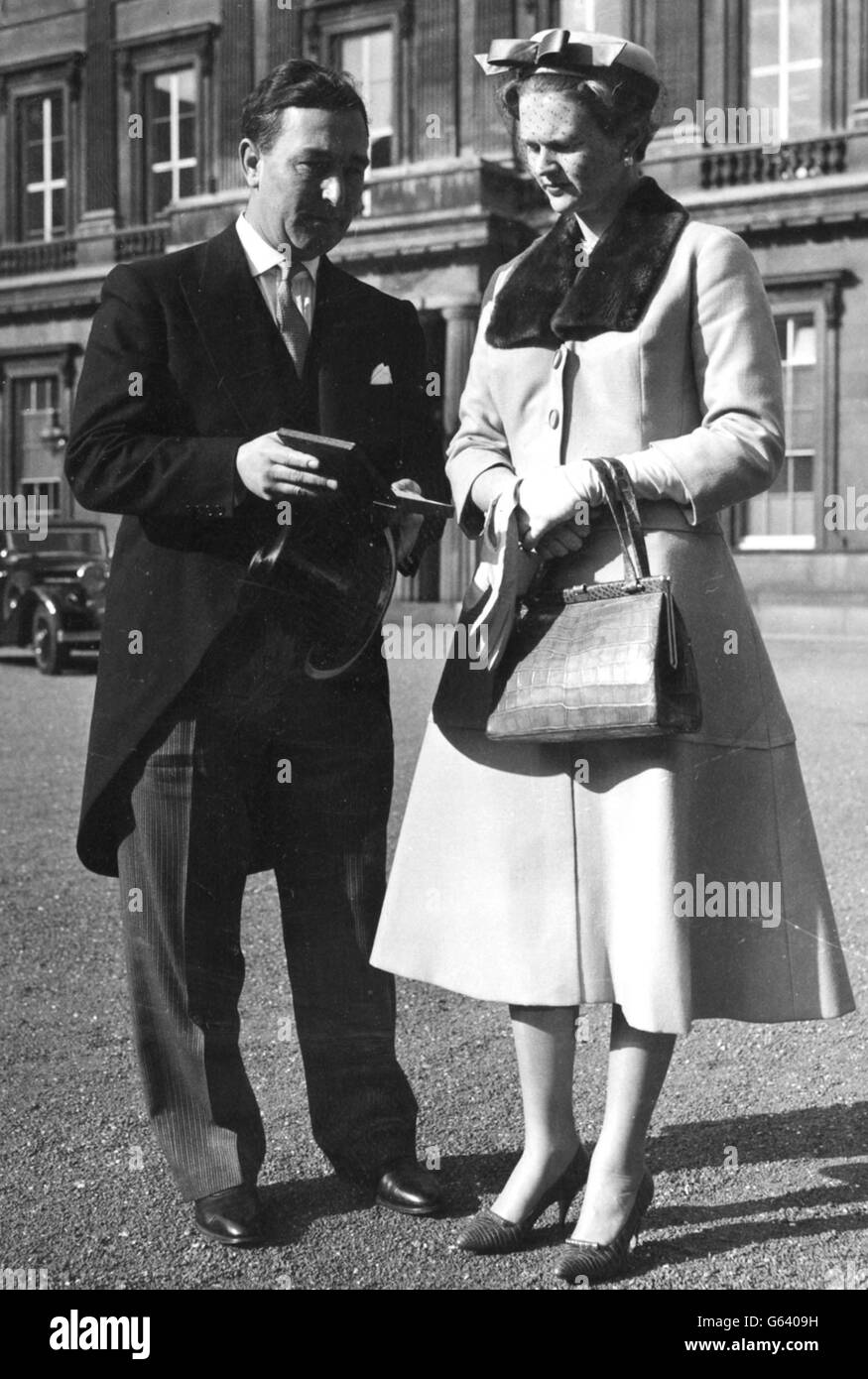 Il Cricketer Denis Compton mostra a sua moglie Valerie le insegne di un Comandante dell'Ordine dell'Impero britannico (CBE), che aveva appena ricevuto dalla Regina, quando lasciarono Buckingham Palace dopo l'investitura. Foto Stock
