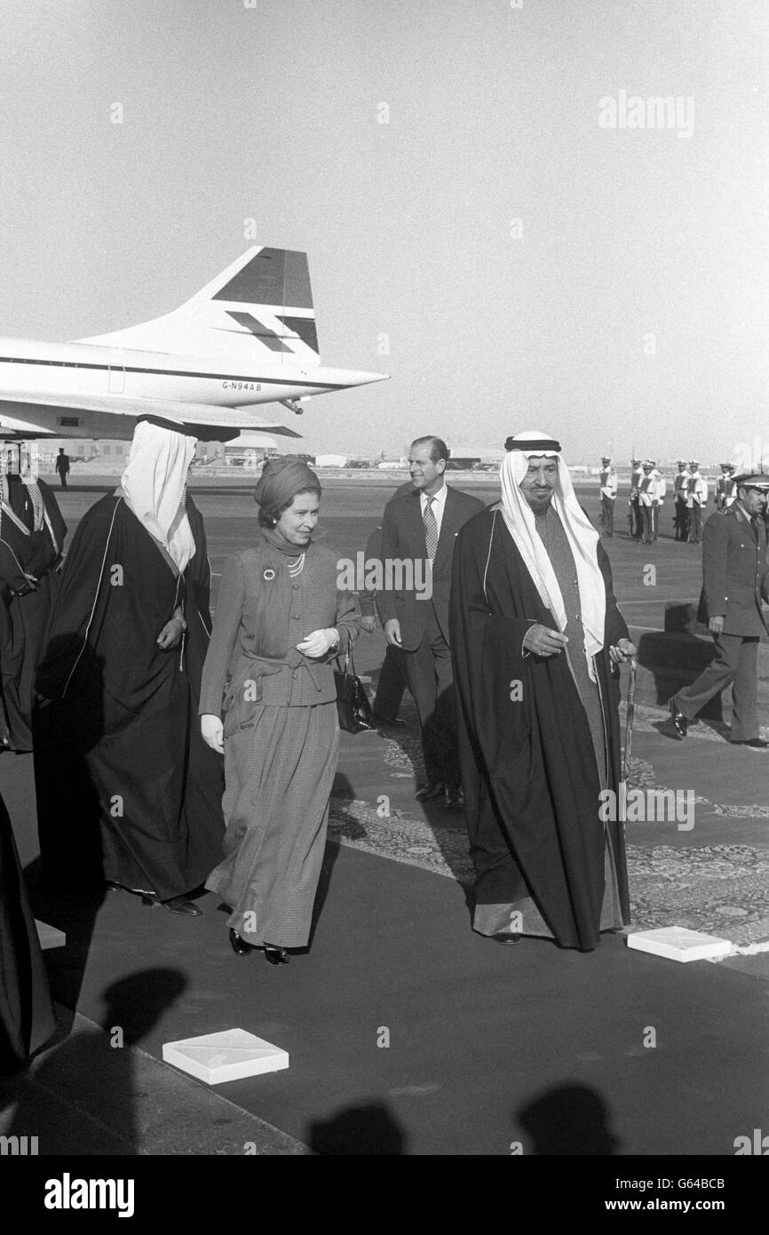 La Regina e il Duca di Edimburgo (dietro) sono stati accolti dal re Khalid all'aeroporto di Riyadh all'inizio della loro visita in Arabia Saudita, l'ultima tappa del loro tour di tre settimane del Medio Oriente. Indossa un lungo abito blu zaffiro che la copre dalla testa ai piedi. Ciò è stato in conformità con la legge islamica - rigorosamente osservata dai sauditi - che richiede che una donna non deve mostrare né le sue caviglie né le sue braccia. Foto Stock