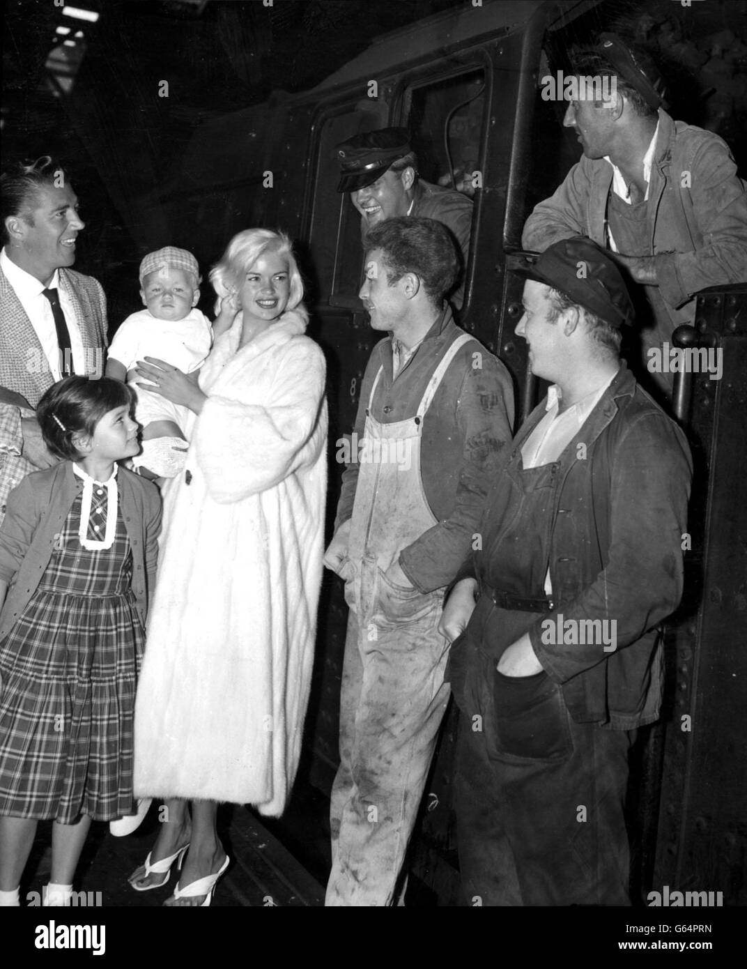 L'attrice di Hollywood Jayne Mansfield tiene con orgoglio il suo figlio di otto mesi Miklos Hargitay mentre chiacchiera con i railwaymen su una piattaforma alla stazione di Euston. Anche visto con l'attrice sono suo marito Mickey Hargitay e otto anni Jayne Marie, figlia del suo primo matrimonio con Paul Mansfield. Foto Stock