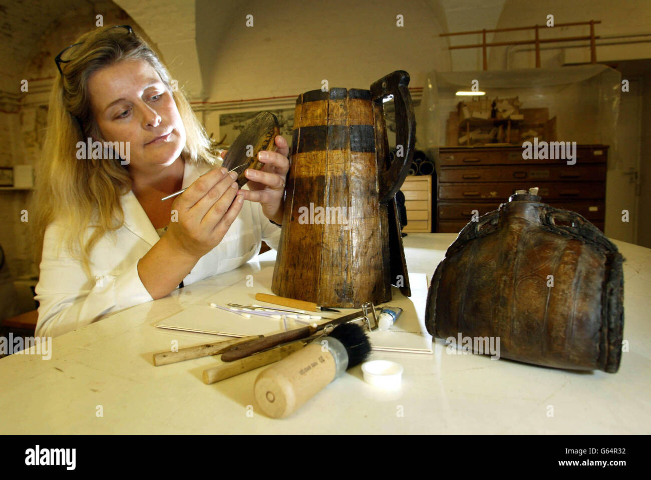 Sue Bickerton, conservatore presso il Mary Rose Trust lavora su un tankard sporco scoperto nel fango all'interno del fulk della famosa nave da guerra Tudor nel porto storico di Portsmouth. * sono 20 anni che l'orgoglio della flotta di Enrico VIII è stato recuperato dalle profondità torbide dell'autunno del Solento 1982. Da allora è stata costantemente spruzzata con acqua in un asciutto-dock controllato in atmosfera per arrestare la disintegrazione delle travi di quercia. Molti elementi sono stati scoperti come gli strati di limo sono gradualmente lavati via compreso la bottiglia di vino di cuoio sulla destra. Fu lanciata nel 1511 e affondò nel 1545. Foto Stock