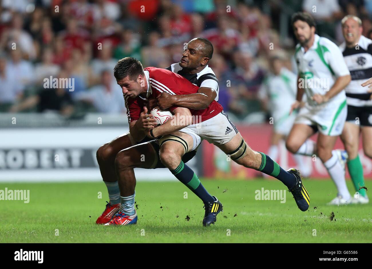 Justin Tipuric dei Lions britannici e irlandesi viene affrontato da Barbarians' Joe Rokocoko Foto Stock