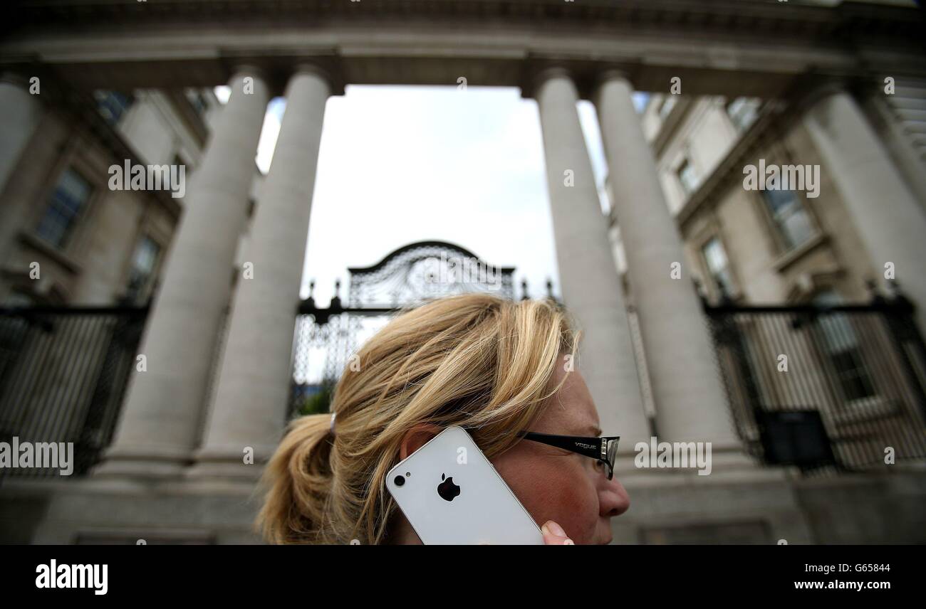 Una donna sul suo iPhone Apple al di fuori degli edifici governativi a Dublino oggi come Taoiseach Enda Kenny ha ribadito che l'Irlanda non negozia specifici accordi fiscali con le singole aziende tra crescenti critiche agli accordi fiscali aziendali di Apple e il suo rapporto con l'Irlanda. Foto Stock