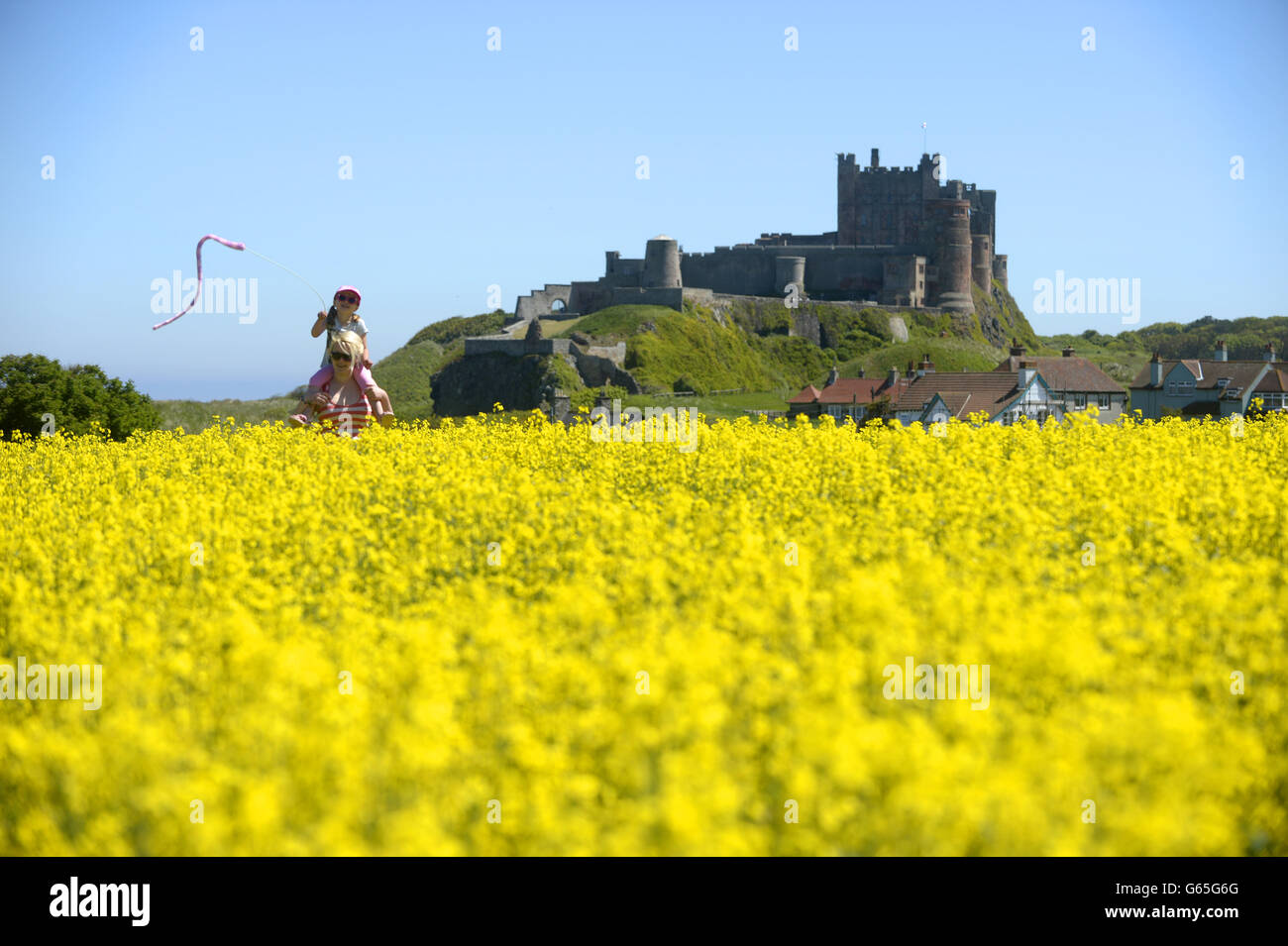 Kadie Lane, 4, e sua madre Stephanie, fare una passeggiata vicino al Castello di Bambburgh a Bamburgh, Northumberland, come il tempo caldo continua. Foto Stock