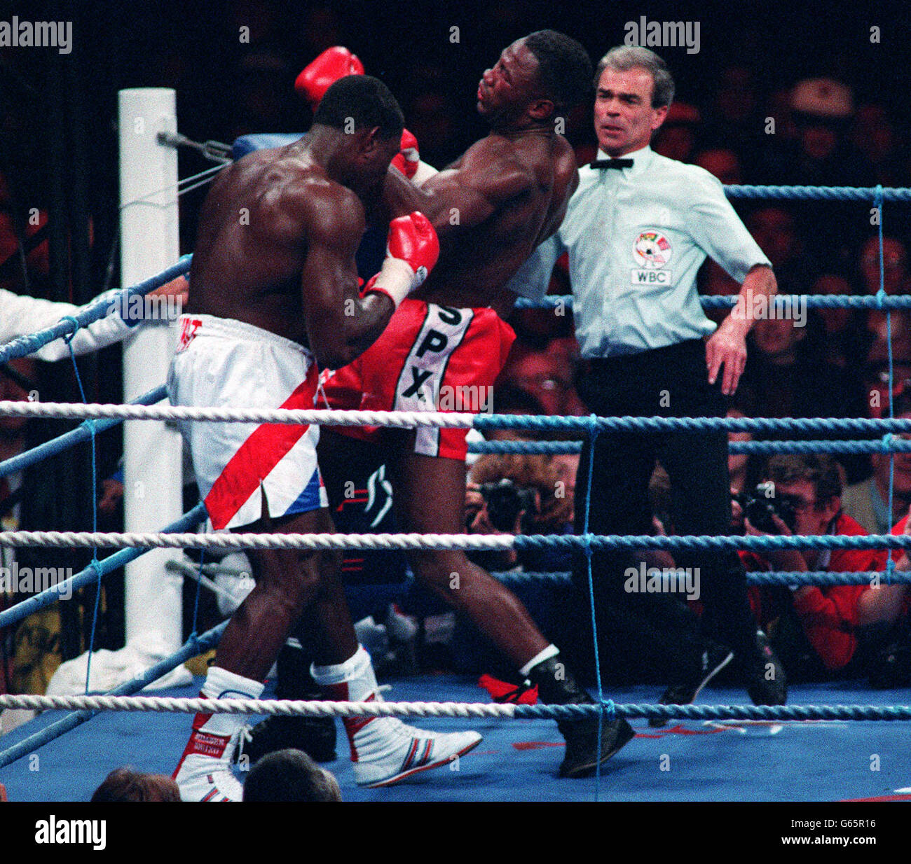 L'allenatore di Frank Bruno, George Francis, entra nel ring mentre Lennox Lewis, il campione dei pesi massimi di WBC, si fa carico della pressione necessaria per battere Bruno nel settimo round. Foto Stock