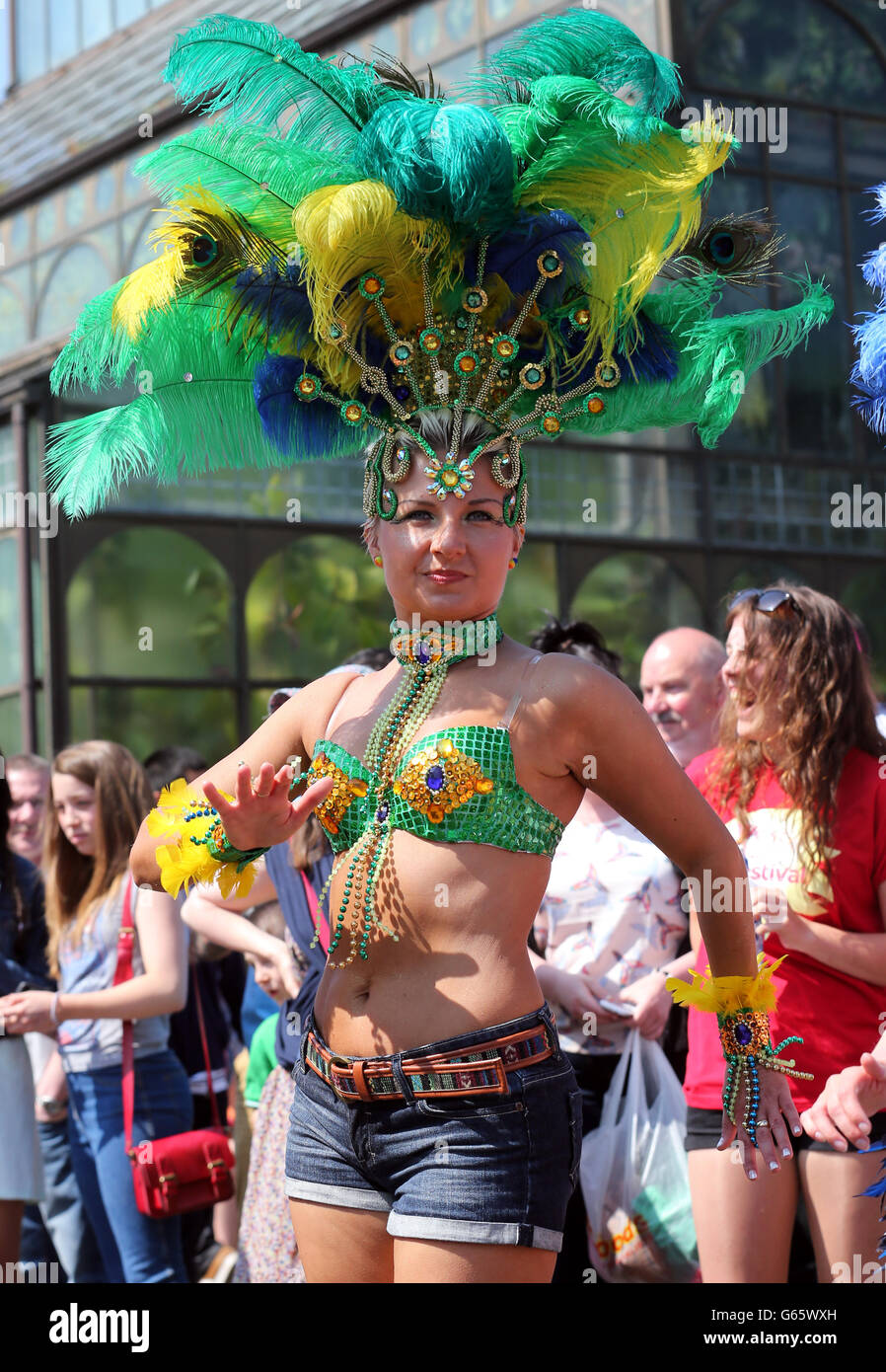 Un membro del gruppo di Samba di Edimburgo che si unì alla sfilata di Mardis Gras, guardata dalla folla su Byres Road a Glasgow. Circa 600 partecipanti si sono Uniti alla sfilata di strada per dare il via al West End Festival, dove si prevede che vi parteciperanno circa 70,000 persone. Foto Stock