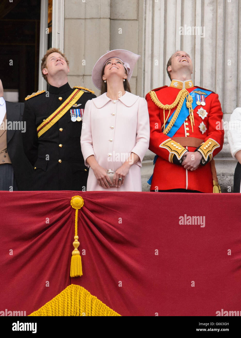 Il Principe Harry e il Duca e la Duchessa di Cambridge, guardano in su mentre guardano un passacalito, dal balcone di Buckingham Palace, nel centro di Londra, dopo l'annuale sfilata di Trooping the Color. Foto Stock