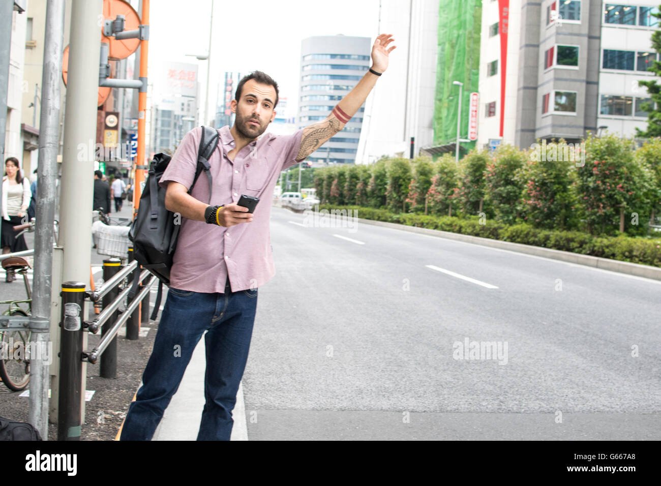 Bianco uomo in piedi in strada con il cellulare salutando uber taxi Foto Stock