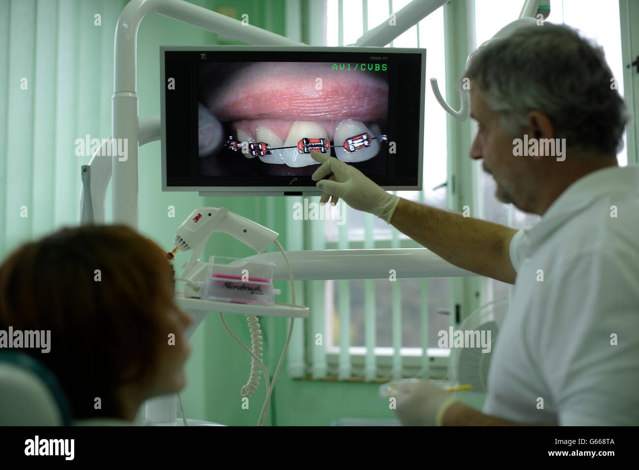 Dentista spiegare al paziente come un rinforzo funzioni Foto Stock