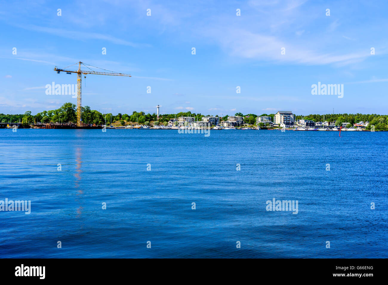 Vastervik, Svezia - 19 Giugno 2016: vista su un mare sito in costruzione e i vicini edifici di appartamenti. Una gru freni Foto Stock