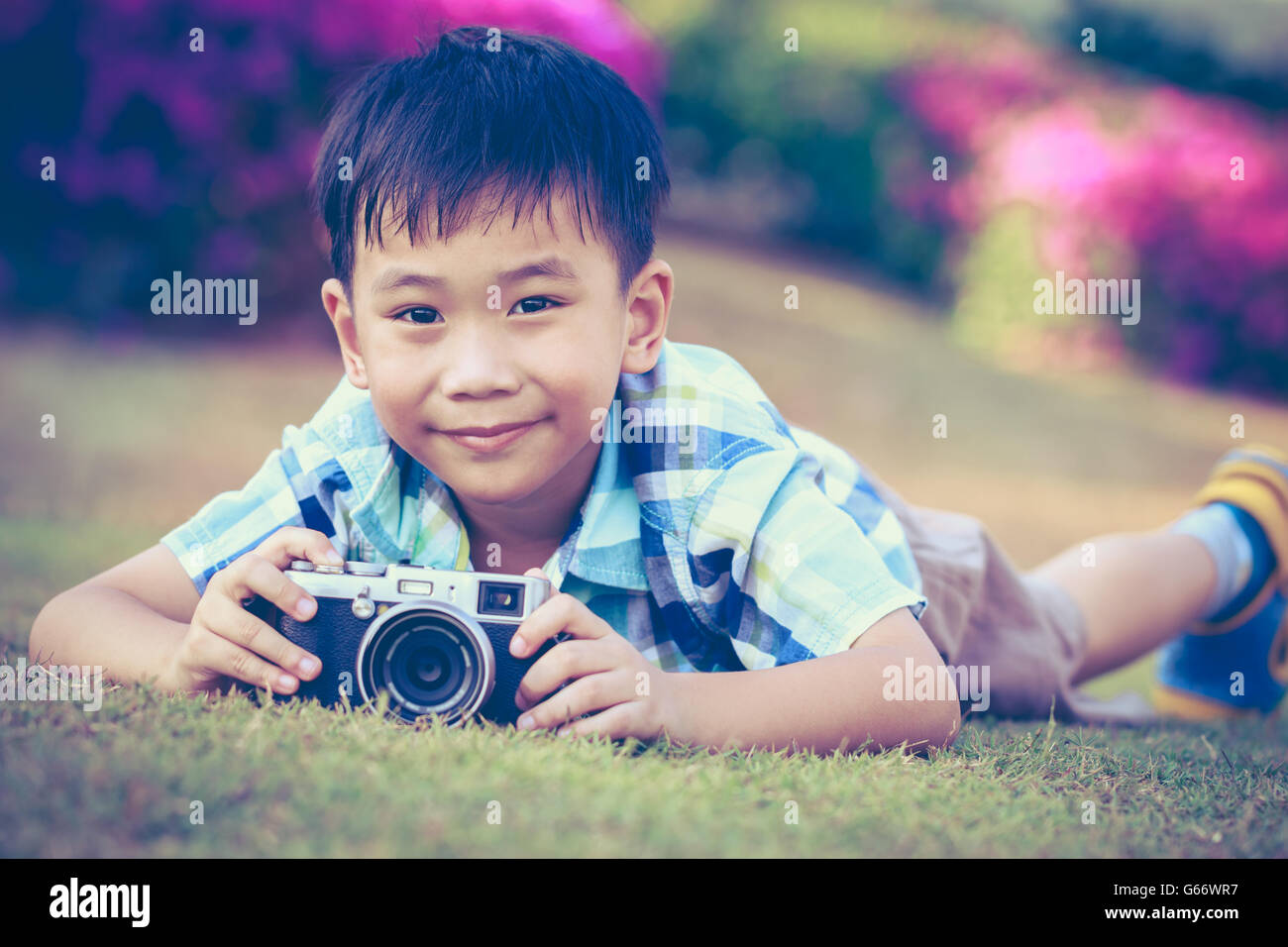 Bel ragazzo asiatico prendendo foto di vintage cinepresa, esplorare la natura al parco, in estate di giorno. Bambino in natura, ou Foto Stock