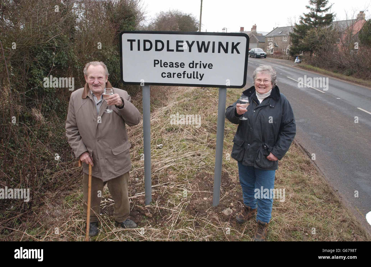 I locali Denis White e Daphne Baxter tostano il loro successo con un nuovo segno e un bicchiere di vino dopo anni di essere stati trascurati, grazie a una campagna di orgogliosi residenti. * il gruppo di otto cottage nel Wiltshire è stato omesso dagli atlanti e si è dimostrato un vero mal di testa per i postmen perplessi e i lavoratori di consegna. Foto Stock