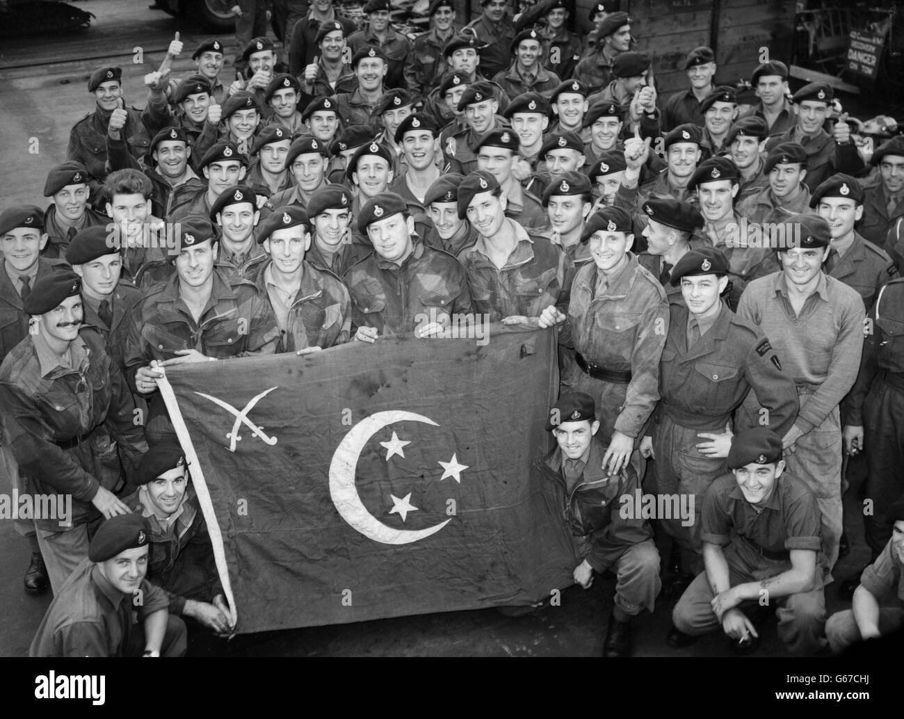 Uomini del 42 Commando, Marines reali, con una bandiera egiziana catturati durante i combattimenti a Port Said. Vengono raffigurati all'arrivo a Devonport a bordo della portaerei della Royal Navy Ocean, che ha svolto un ruolo importante nelle operazioni di Suez Foto Stock