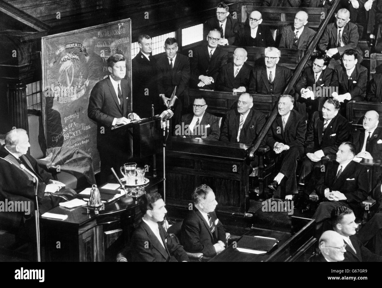 Il presidente americano John F Kennedy si rivolge sia alle Camere del Parlamento irlandese - la prigione e la Seanad - a Leinster House, Dublino, il terzo giorno della sua visita nella Repubblica irlandese. Alle spalle del presidente è vista la bandiera della 69° Brigata irlandese dei volontari di New York, che fu sotto il fuoco nella battaglia di Fredericksburg, una delle battaglie più feroci della guerra civile americana. Kennedy ha presentato la bandiera al popolo irlandese. Foto Stock