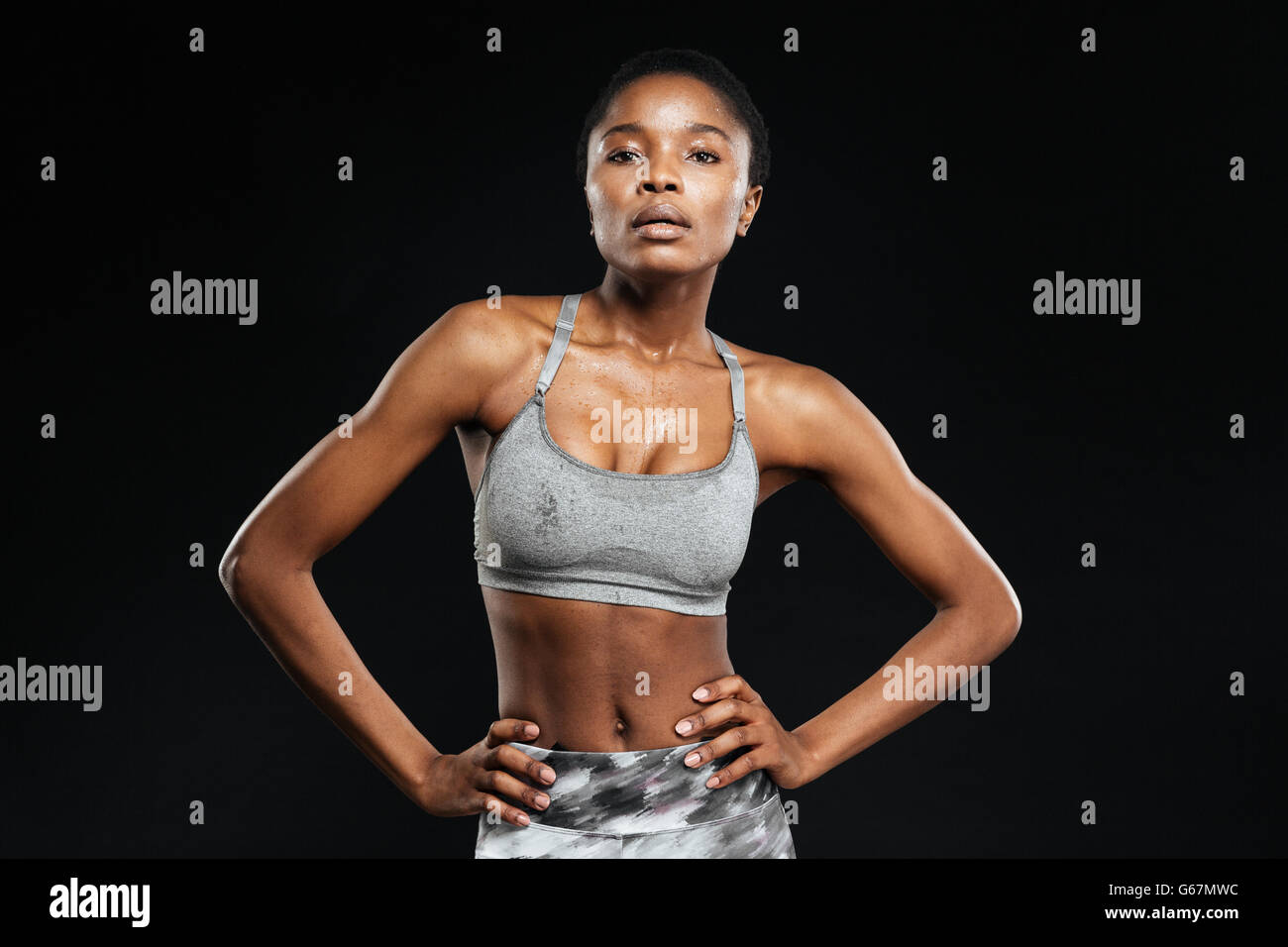 Ritratto di un fitness afro american donna posa isolata su uno sfondo nero Foto Stock