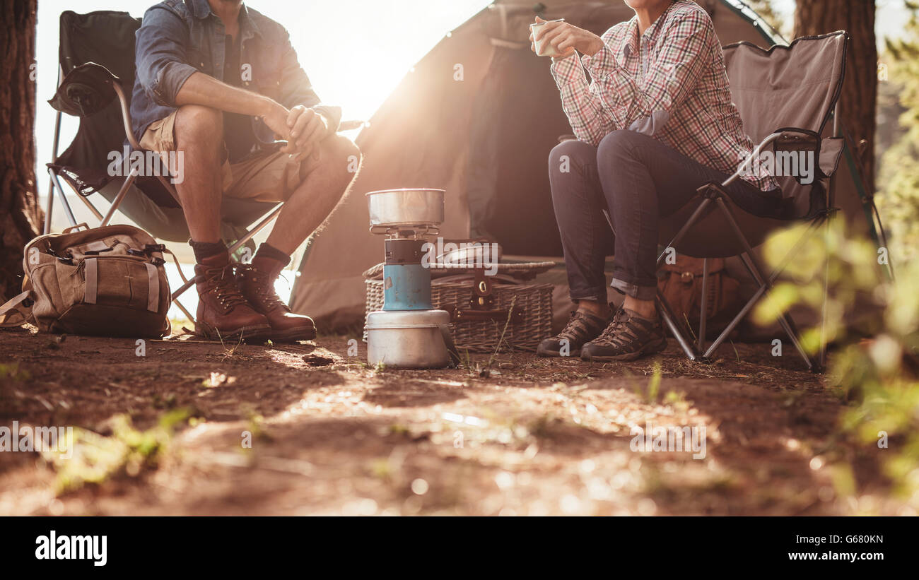 Immagine ritagliata di un uomo e di una donna seduta in sedie al di fuori della tenda. Giovane camping nella foresta. Foto Stock