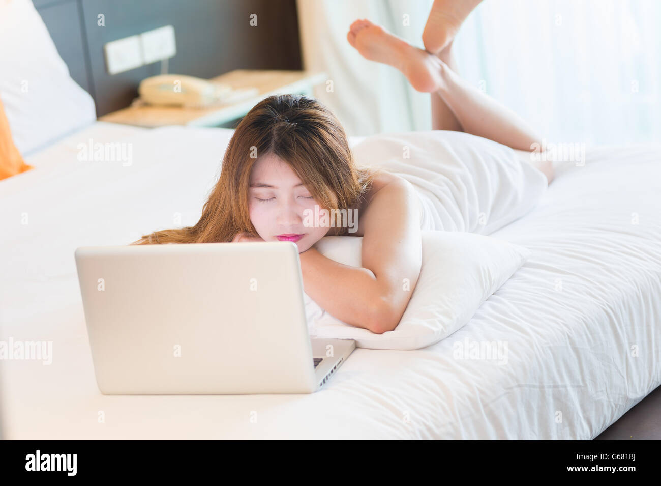 Bella giovane donna in accappatoio addormentato mentre utilizzando laptop nel letto di casa Foto Stock