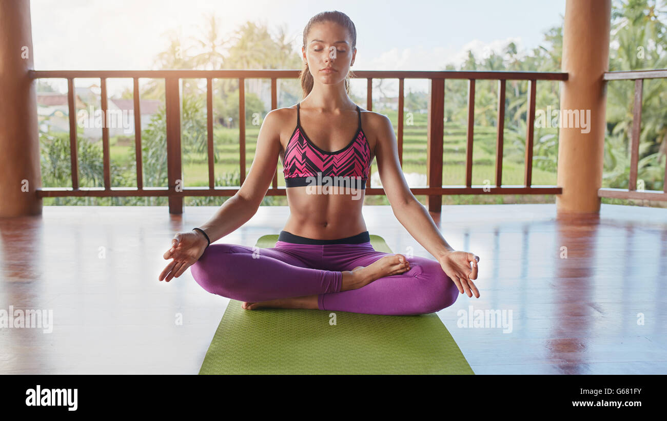 Colpo di montare la giovane donna meditando in lotus yoga posa al centro di salute. Un sano giovane femmina la pratica dello yoga, lei è seduta sul Foto Stock