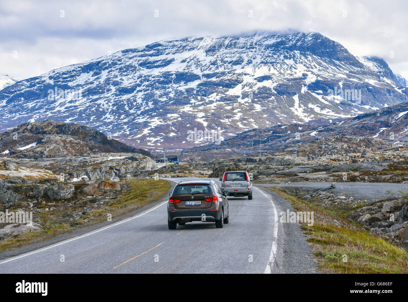 Vetture attraversando la Norvegia Svezia confine attraverso montagne innevate, traffico di veicoli a motore sulla strada E10 vicino a Riksgränsen Foto Stock