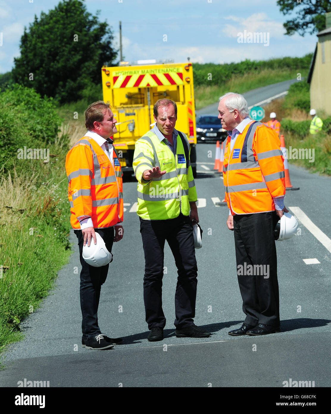 Benvenuti nello Yorkshire Chief Executive Gary Verity (a sinistra), Direttore del Tour de France Christian Prudhomme e leader del Consiglio della Contea dello Yorkshire del Nord John Weighell (a destra) studiano la superficie stradale appena posata vicino a West Tanfield, Ripon, mentre le autostrade sono preparate prima dell'inizio del Tour de France nello Yorkshire nel 2014. Foto Stock