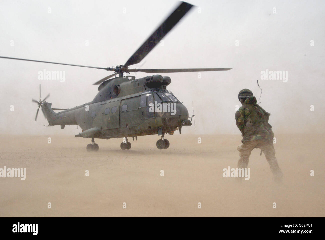 Una Puma britannica della Royal Air Force Joint Helicopter Force si prepara a decollo mentre un maestro di carico guarda durante una pratica operazione di assalto aereo per catturare i campi aerei nemici, nel deserto fuori Kuwait City. Foto Stock